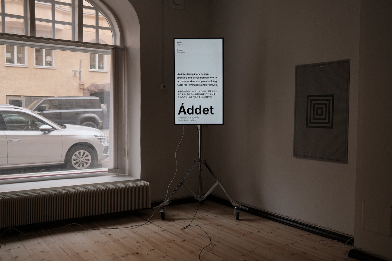 A vertical screen on a tripod standing in the window of the Tehtaankatu office, displaying an ad